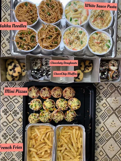 A party spread featuring modern favorites like Hakka Noodles, White Sauce Pasta, Mini Pizzas, French Fries, and desserts.