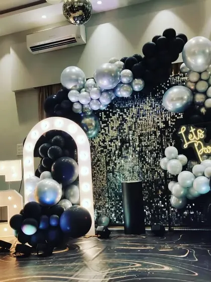 This 25th birthday party had a fun, disco vibe. I used a black and silver balloon garland, a silver shimmer wall, and large light-up '25' marquee numbers to create an exciting and festive atmosphere perfect for celebrating.