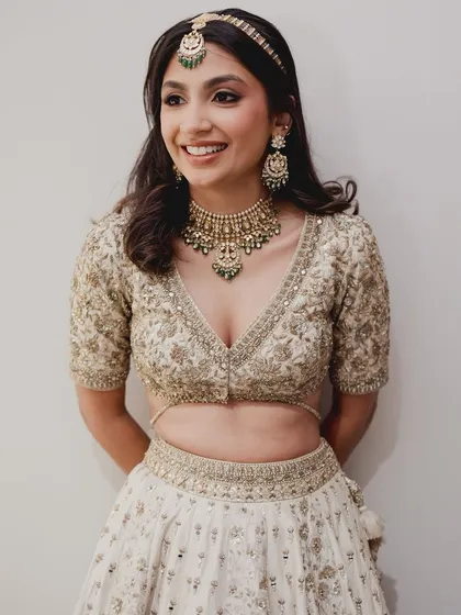 A full portrait of this bride in her gorgeous ivory and gold lehenga. The entire look is one of effortless grace.