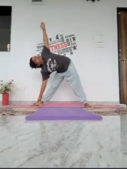 An instructor demonstrates Trikonasana (Triangle Pose) during a mid-morning online class. This classic standing pose stretches the entire side of the body and improves balance and stability.