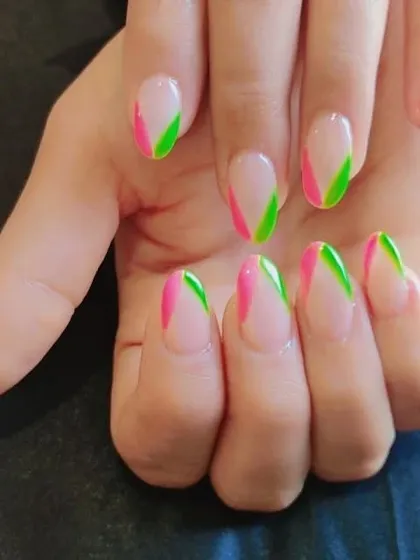 A close-up of the modern French manicure with diagonal pink and green tips.