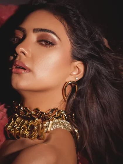 This close-up portrait uses motion blur and warm lighting to create an artistic, high-fashion feel. The focus is on the unique gold choker and the model's intense gaze.