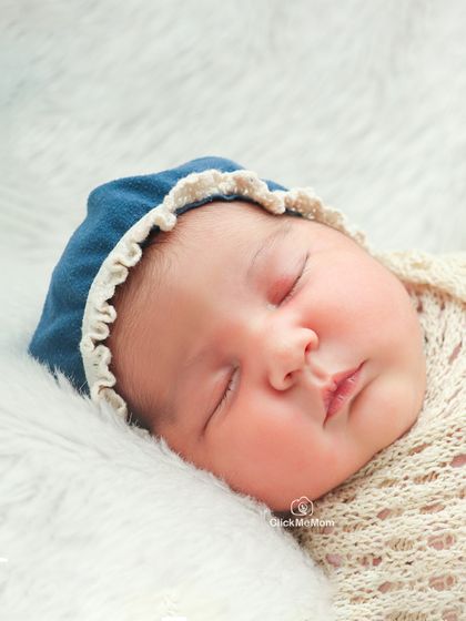 A close-up portrait of a newborn's face, with a simple blue bonnet framing their features. This shot is all about capturing their pure and innocent expression.