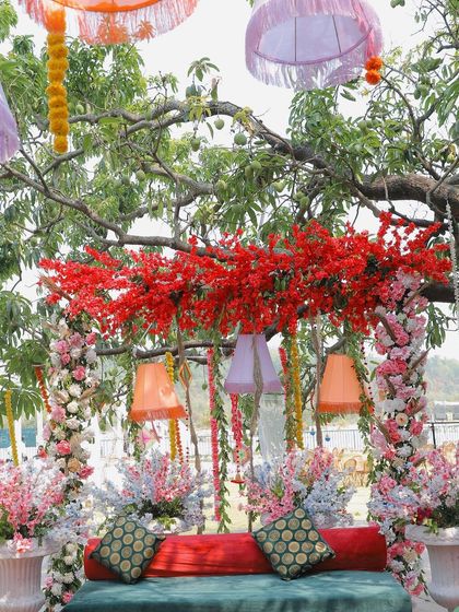 A shot of the vibrant, bohemian-style decor at a mehendi ceremony, with colorful lampshades and floral arrangements.