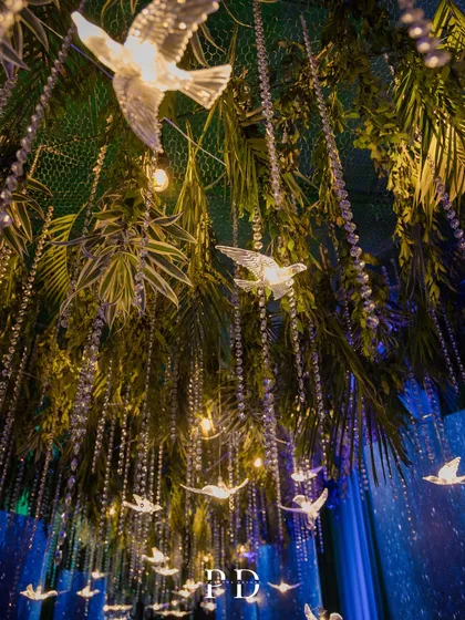 A close-up of the hanging decor from the celestial sangeet, featuring crystal birds, delicate light strings, and lush greenery. It's these details that make a theme come alive.