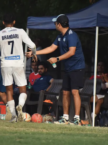 A coach giving instructions to a player coming off the bench. Tactical awareness and squad depth are crucial to our game plan.