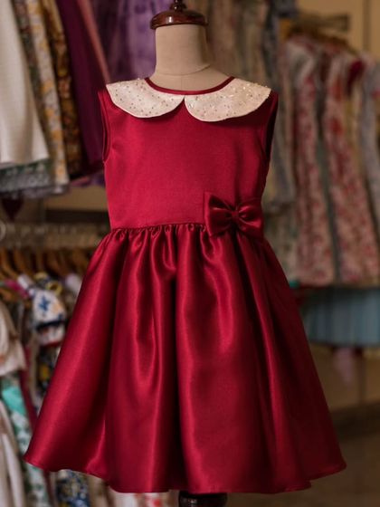 A classic red satin party dress on display. The full skirt is perfect for twirling, and the sequined collar adds just the right amount of festive sparkle.