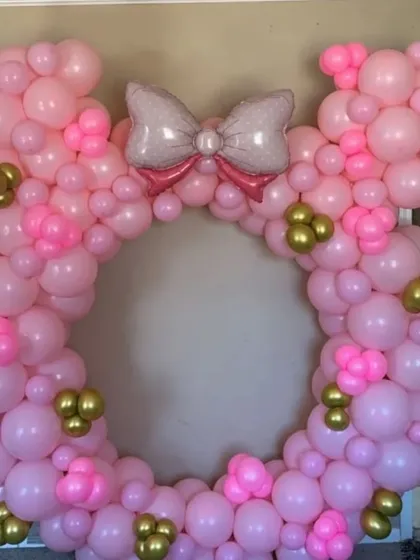 A Minnie Mouse-shaped balloon ring, perfect as a photo booth for a themed party. The frame is made entirely of pink and gold balloons.