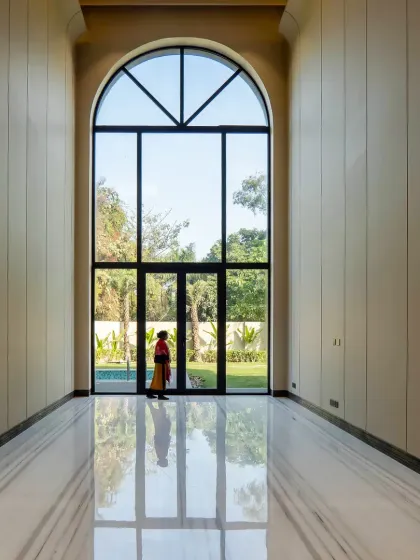 Inside the Sultanpur farmhouse, this double-height archway is a perfect example of neo-classical elegance meeting modern simplicity. The grand scale, combined with Equator White marble floors, creates a light-filled, inviting space that connects seamlessly with the outdoors.