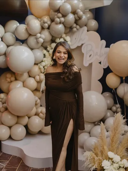 The radiant mother-to-be at her teddy bear-themed baby shower, perfectly complementing the neutral and elegant balloon backdrop.
