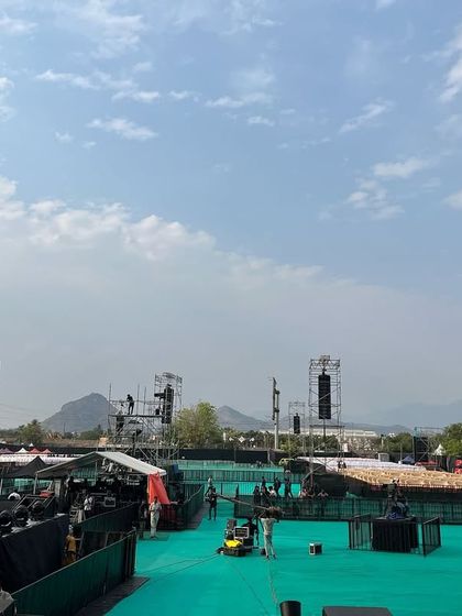 A panoramic view of the Harris Jayraj concert venue in Salem during setup. This shot captures the scale of the open-air arena we constructed, including delay towers for sound, ensuring coverage for a massive crowd.