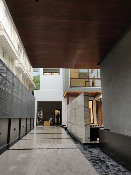 The completed entryway of a modern home, with polished marble flooring, a wood-paneled ceiling, and a finished marble feature wall.