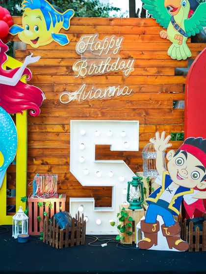 A birthday setup combining mermaid and pirate themes, featuring a large light-up number '5' and character cutouts.