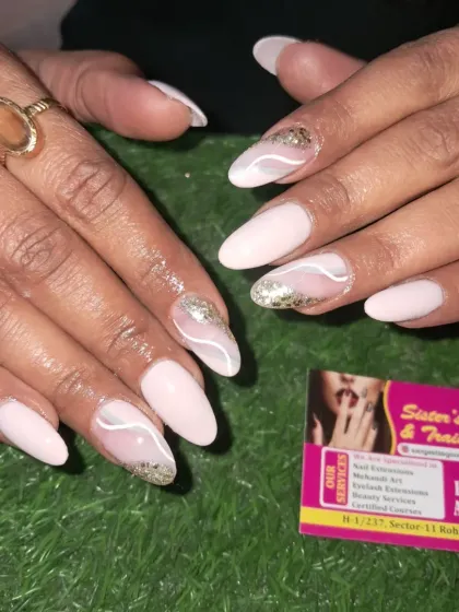 A beautiful nude nail set with abstract white lines and gold glitter accents for a touch of elegance.