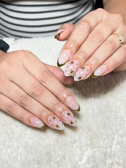 A nude base with a gold chrome French tip and delicate star details. This celestial-themed design is both elegant and whimsical.