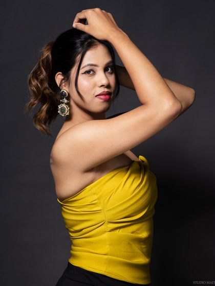 A model in a yellow top, with her hands in her hair, showing a fun and energetic vibe.