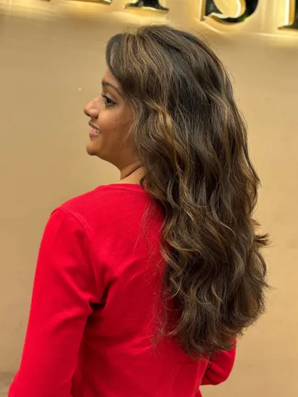 A side view of a client's new hair color, showing the beautiful blend of tones and the soft, flowing waves.
