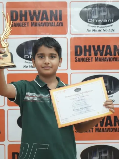 A student proudly holds his certificate and trophy.