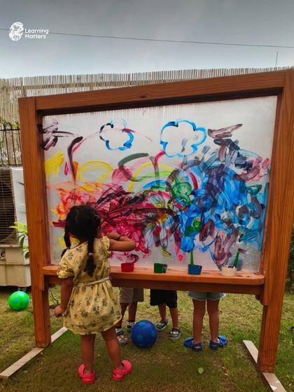 An outdoor transparent easel changes the perspective on painting. Children can paint the world they see through the screen, collaborate with a friend on the other side, and experience art as a shared, dynamic process.
