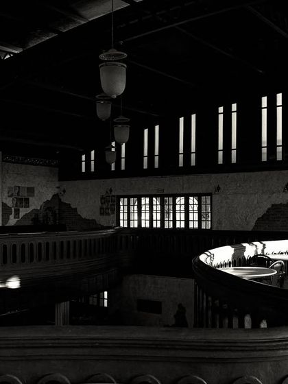 The play of light and shadow across the curved mezzanine. The high-contrast lighting creates a dramatic and moody effect.