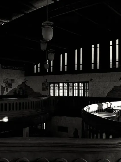 The play of light and shadow across the curved mezzanine. The high-contrast lighting creates a dramatic and moody effect.