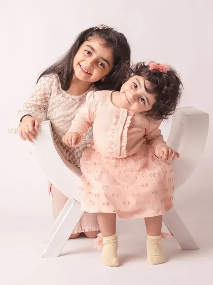 Two sisters, two beautiful smiles. Their matching outfits and playful poses make for an absolutely adorable sibling portrait.