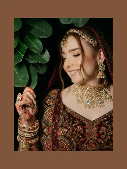 A joyful bridal portrait, her smile lighting up her face as she admires her henna-adorned hands.