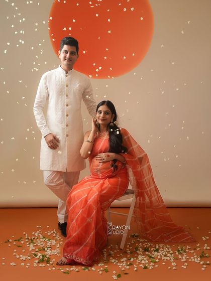 A classic couple portrait from a traditional maternity session. They stand together against a warm, artistic backdrop, creating a memory that feels both regal and deeply personal.