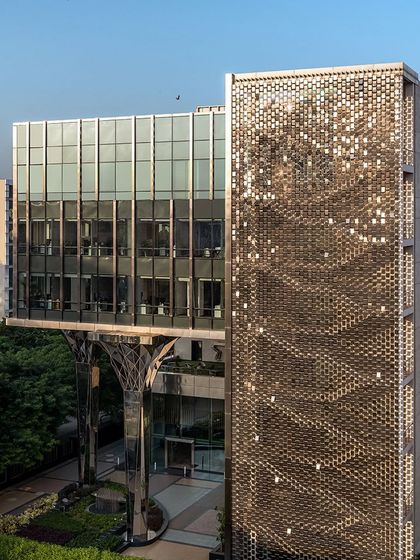 The 'shimmer screen' façade during the day, with the sun creating a wave-like pattern of reflections across the steel panels.