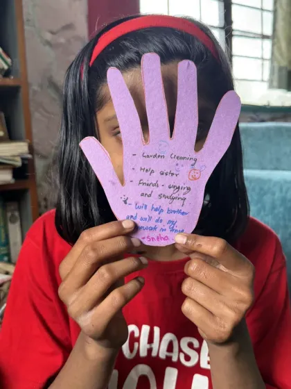 A girl holds up a hand-shaped cutout with her promises of kindness written on it. After reading "The Lion Who Wanted to Love," this activity helped children think about how they can bring more kindness into their own lives.