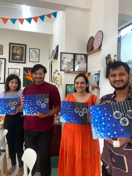 A group of participants proudly holding up their finished night sky paintings. The sense of community and shared creativity is a big part of the experience.