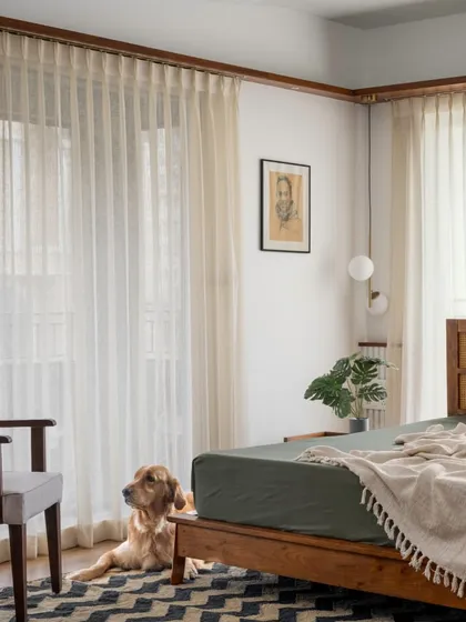 The master suite in 'Vasudhalayah' is a peaceful haven, with sunlit French windows framed by our signature wooden ledges and a classic bed with a cane headboard.