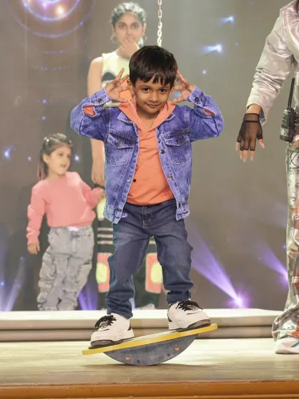 Balance is fundamental. This young performer confidently uses a balance board on stage, demonstrating the improved motor skills and physical control gained through our specialized training activities.