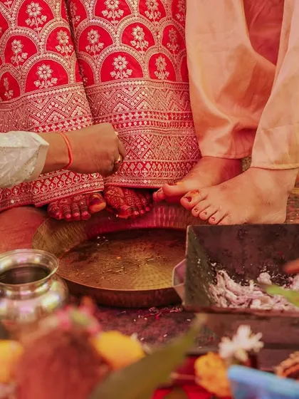 A close-up shot focusing on the traditional wedding rituals involving the couple's feet and the sacred fire.