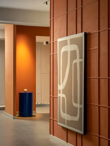 This shot shows the relationship between different zones. The view moves from the terracotta paneled wall in the foreground to the orange accent wall in the back, creating visual depth and interest.