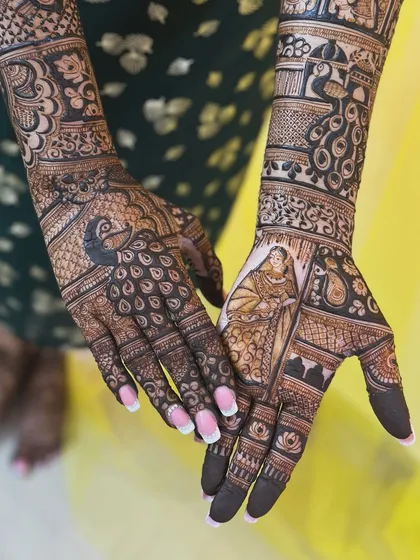 A closer look at the back of the hands from a student's bridal mehendi. The design features a beautiful peacock and a bride in a palanquin, telling a story with every detail.