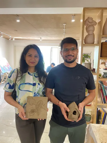 A couple proudly displays the clay house and carved tile they made during a creative date.