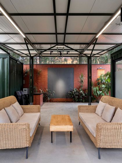 An open-air meeting area nestled between two container office modules. Furnished with comfortable wicker sofas, this space provides a relaxed setting for team discussions or client meetings, blending work with nature.