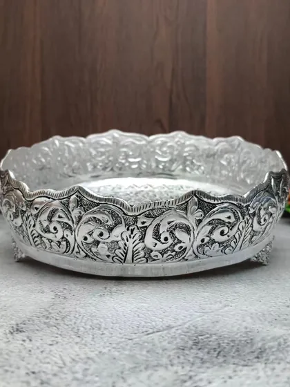 An antique German silver urli with a peacock and floral vine pattern along its sides, a truly artistic piece.