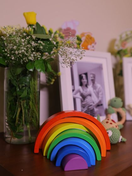 A wooden rainbow stacking toy adds a pop of color to the neutral-toned decor, symbolizing hope and joy for the new arrival.