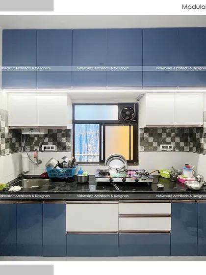 A completed modular kitchen with a two-tone acrylic finish in blue and white. The design includes overhead cabinets for ample storage and under-cabinet lighting for a well-lit workspace.
