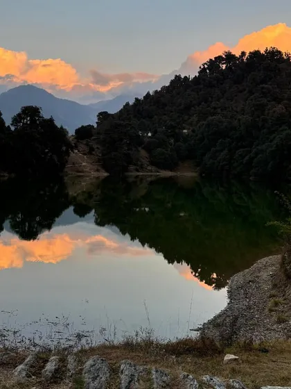 The sky paints a masterpiece over Deoria Tal at sunset. The reflection of the colorful clouds on the calm water is a sight to behold.