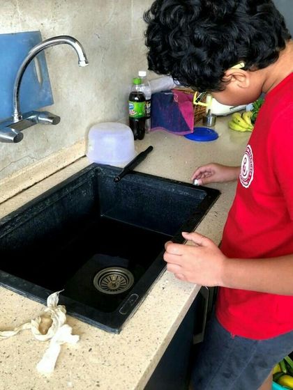 A young boy learns about sink plumbing by examining the components of a kitchen sink. Understanding how things work is the first step to being able to fix them.
