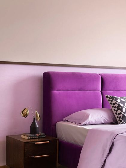 For a client who loves rock music and the color purple, I designed this bold bedroom. A rich purple velvet headboard is set against a dual-toned wall, creating a space that is full of personality.
