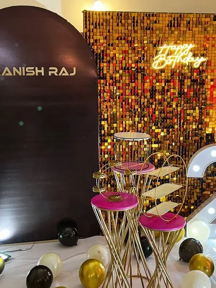 A 23rd birthday party backdrop combining a custom panel with a gold sequin wall, marquee numbers, and a black, white, and gold balloon arrangement.