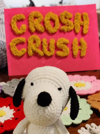 My crochet Snoopy figure posing proudly in front of my "Croshcrush" sign at an exhibition.