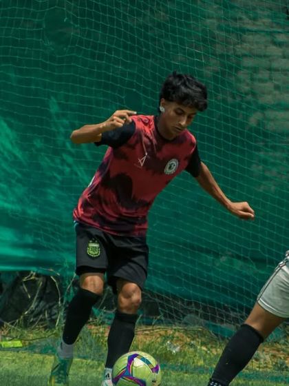 A player skillfully dribbles around a defender near the corner of the field.
