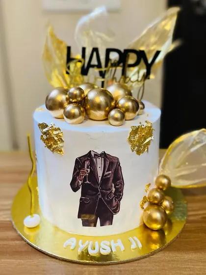 An elegant cake for a man, featuring a tuxedo print and gold decorations.