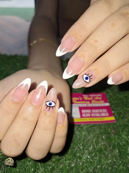 A classic French manicure with a protective evil eye accent. These almond-shaped nails are perfect for an everyday look that is both chic and meaningful.