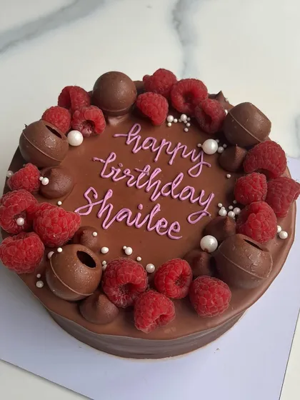 A rich chocolate cake topped with fresh raspberries and chocolate spheres. The combination of dark chocolate and tart raspberries is a classic for a reason.